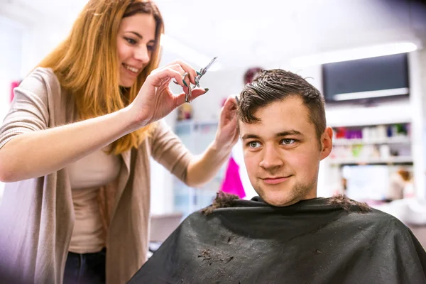 Hairdresser cutting hair of young client. — Stock Photo, Image