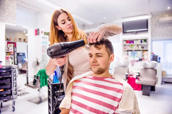 Sušení vlasů kadeřnice klientovi. — Stock fotografie