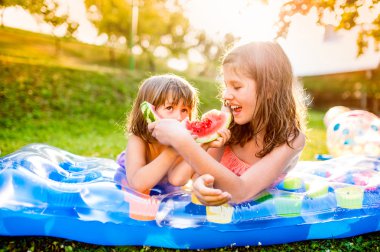 İki kız karpuz yiyor.  