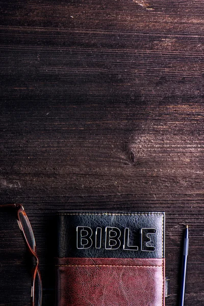 Bíblia, óculos e caneta na mesa — Fotografia de Stock