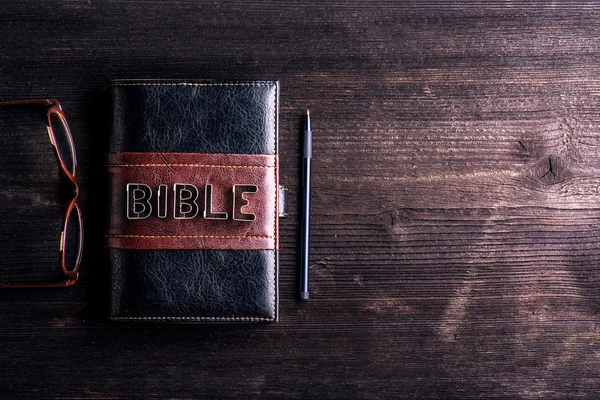 Biblia, anteojos y pluma en la mesa — Foto de Stock