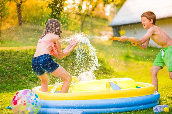 Boy splashing girl with water gun — Stock Photo, Image