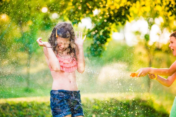 Jongen spetterend meisje met waterpistool — Stockfoto