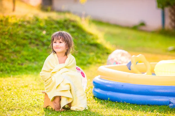 Chica en toalla sentada junto a la piscina — Foto de Stock