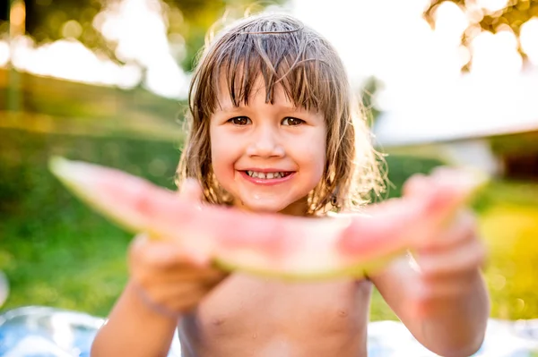 Liten flicka äter vattenmelon i trädgården — Stockfoto