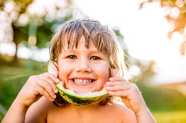 Liten flicka äter vattenmelon i trädgården — Stockfoto