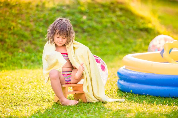 Chica en toalla sentada junto a la piscina — Foto de Stock