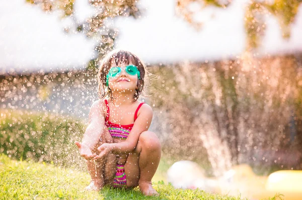 Meisje onder water spatten van sprinkler — Stockfoto