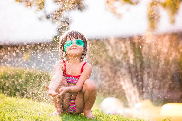 Flicka under vatten stänk från sprinkler — Stockfoto