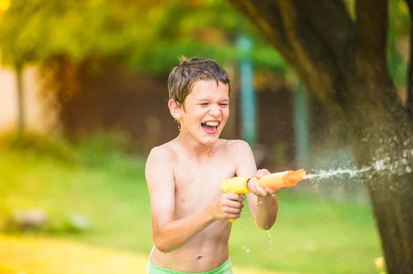 Jongen spatten met waterpistool — Stockfoto