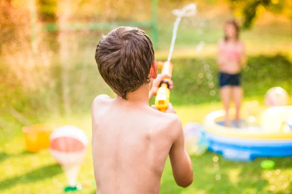 Junge bespritzt Mädchen mit Wasserpistole — Stockfoto