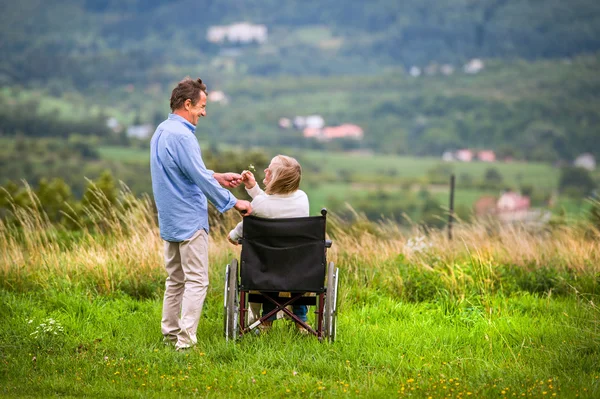 Senior man with woman in wheelchair, green autumn nature — Stock Photo, Image