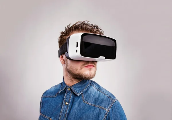 Man wearing virtual reality goggles. Studio shot, gray backgrou — Stock Photo, Image