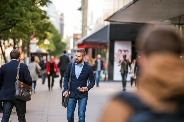 Hipster manager with smart phone walking in the street — Stock Photo, Image