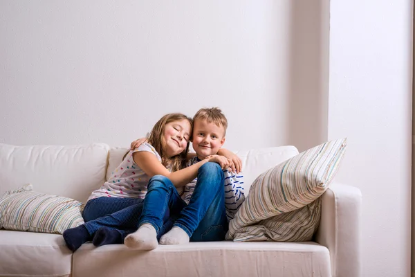 Junge und Mädchen sitzen auf einer weißen Couch. Kopierraum. — Stockfoto