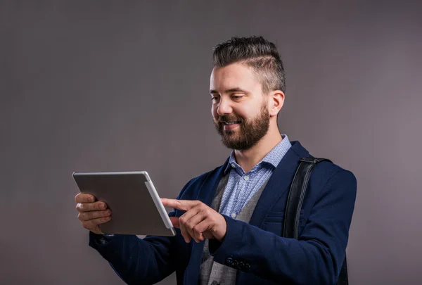 Hipster biznesmen z tabletem, strzał studio, szare tło — Zdjęcie stockowe