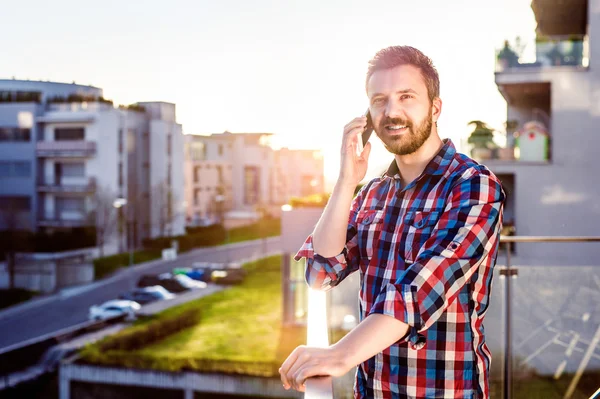 Podnikatel s smartphone telefonní hovor, stojící na balco — Stock fotografie
