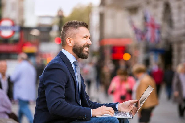 Manajer Hipster yang bekerja pada laptop di Circus Piccadilly yang cerah, Lo — Stok Foto