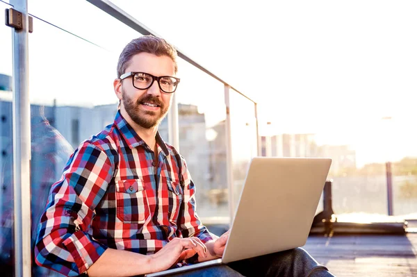 Бизнесмен работает из дома на ноутбуке, сидит на балконе — стоковое фото