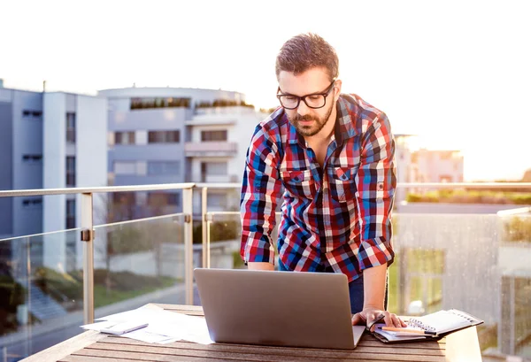 Homme d'affaires travaillant de la maison sur ordinateur portable, debout sur le balcon — Photo