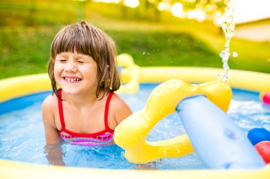 Küçük kız bahçede yüzme havuzunda eğleniyor..