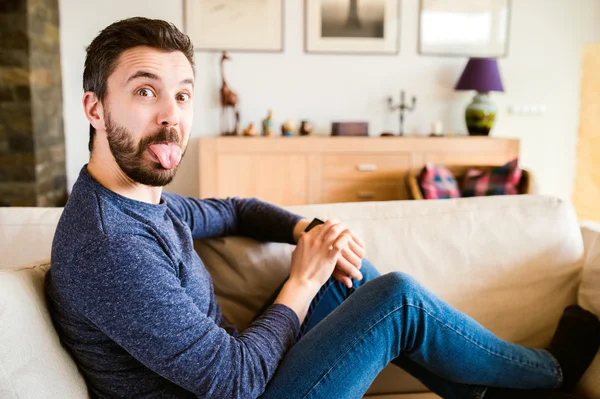 Hombre en casa sentado en el sofá usando reloj inteligente —  Fotos de Stock