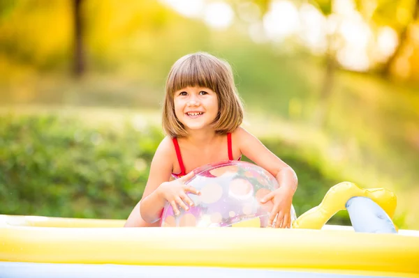 Kleines Mädchen mit Ball im Garten-Schwimmbad. — Stockfoto