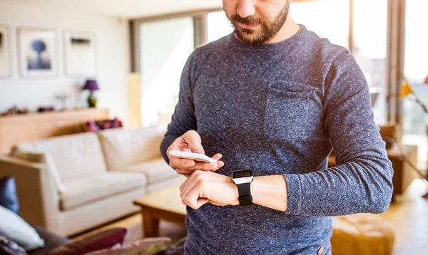 Man som arbetar hemifrån med hjälp av smartphone och smart Watch-klocka — Stockfoto