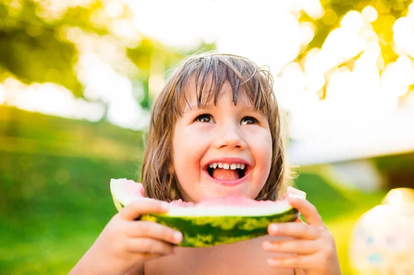 Söt liten flicka äter vattenmelon i soliga sommarträdgård — Stockfoto