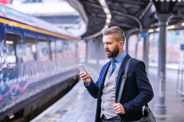 Uomo d'affari con smartphone alla piattaforma ferroviaria — Foto Stock