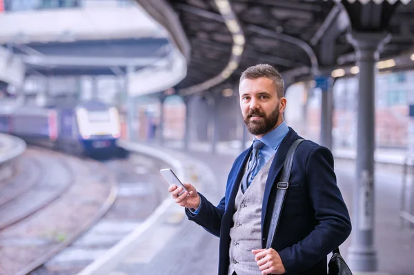 Hombre de negocios con smartphone esperando tren —  Fotos de Stock