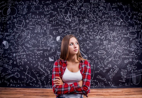 Estudante contra um grande quadro negro com símbolos matemáticos — Fotografia de Stock