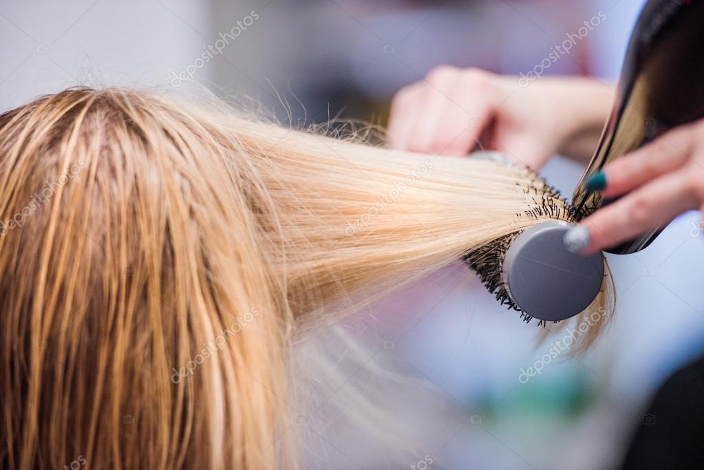 cabeleireiro secando o cabelo de seu cliente com um secador de