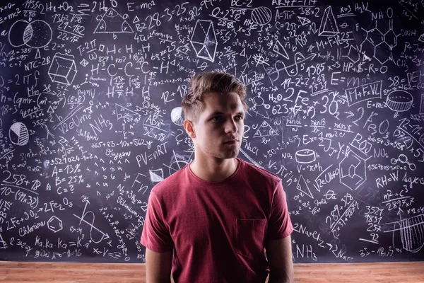 Student mot en stor svart tavla med matematiska symboler — Stockfoto