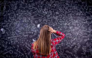 Öğrenci matematiksel semboller ile büyük bir tahta karşı