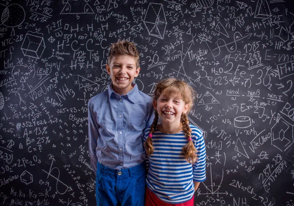 Menino e menina feliz na escola contra o grande quadro negro . — Fotografia de Stock