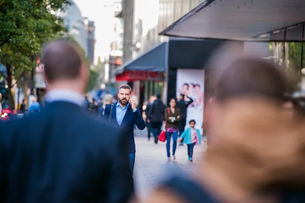 Hipster manager with smart phone walking in the street — Stock Photo, Image
