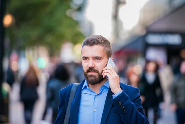 Менеджер хіпстерів зі смартфоном, що йде по вулиці — стокове фото
