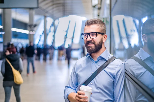 Hipster empresário segurando uma xícara de café, estação de metrô — Fotografia de Stock