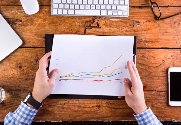 Zakenman werken met grafiek, het dragen van slimme horloge, houten rug — Stockfoto