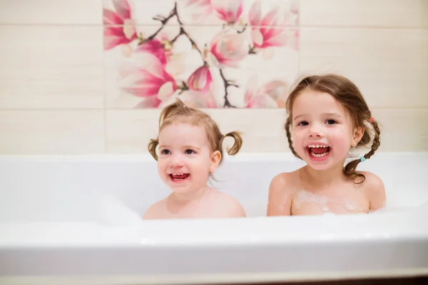 Две маленькие девочки принимают ванну с пузырьками в ванной — стоковое фото