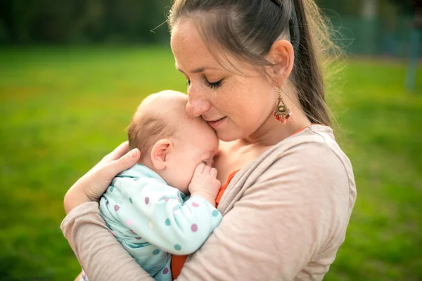 Mother holding her baby daughter, outside in spring nature — Stock Photo, Image
