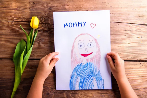 Dziewczynka gospodarstwa rysunku jej matki i żółty tulipan. — Zdjęcie stockowe