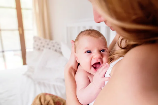 Mladá matka drží její syn novorozeně, domácí ložnice — Stock fotografie