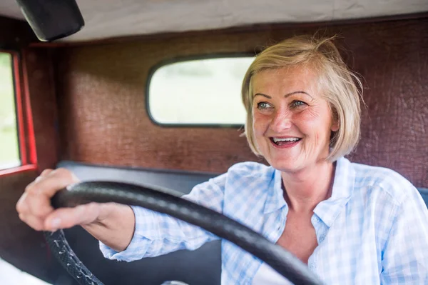 Mulher sênior dentro do caminhão vintage — Fotografia de Stock