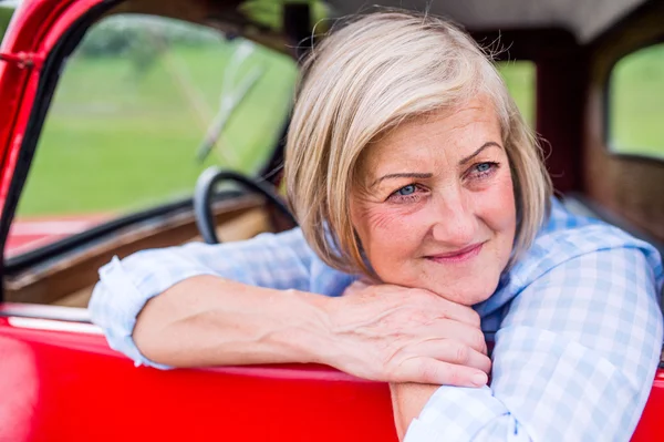 Senior woman inside vintage truck — Stock Photo, Image