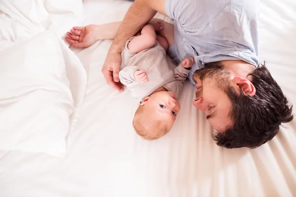 Baby boy on bed with father — Stock Photo, Image