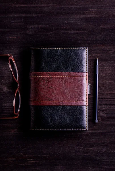 Livro, óculos e caneta sobre mesa de madeira — Fotografia de Stock