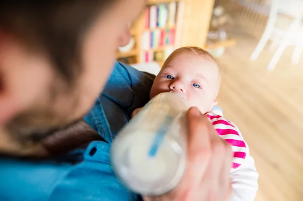 Junger Vater trägt und füttert seinen neugeborenen Sohn — Stockfoto