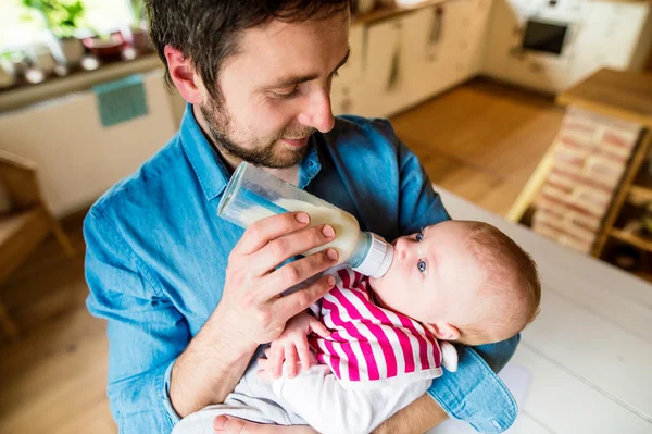 Young father carrying and feeding his newborn baby son — Stock Photo, Image